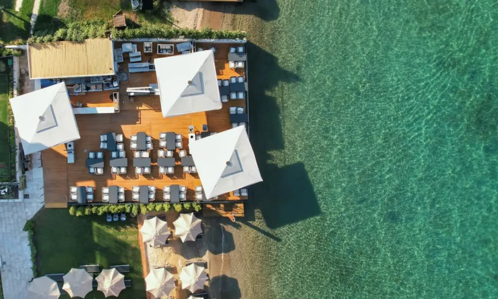 Miya Beach Bodrum’da beyaz kum plaj, ahşap iskele, şezlonglar ve Tilkicik Koyu’nun turkuaz denizi