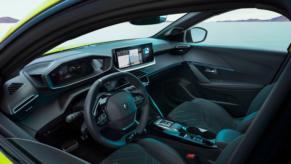 Peugeot e-208 elektrikli B-hatchback otomobilin modern ve sportif iç mekan tasarımı, dinamik direksiyon simidi, yüksek konumlu dijital i-Cockpit gösterge paneli ve geniş dokunmatik multimedya ekranıyla sürücü odaklı bir deneyim sunuyor.