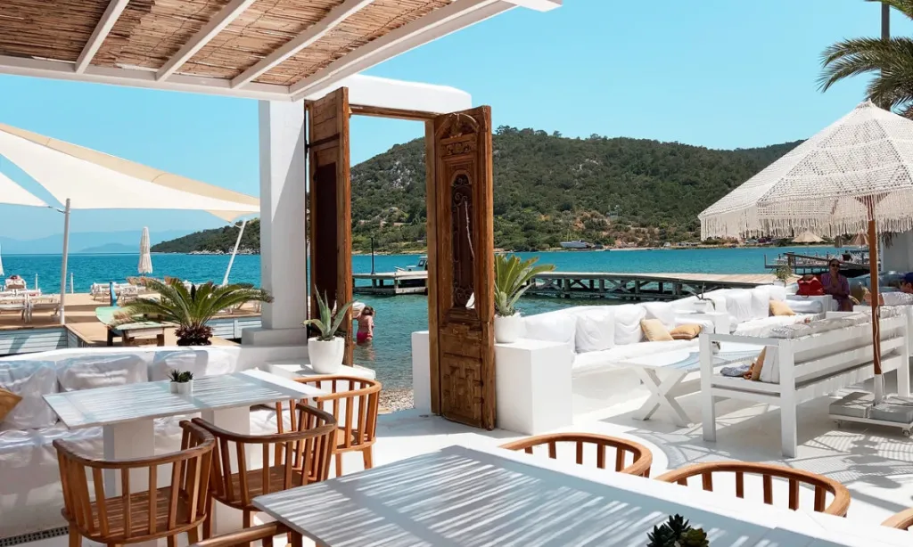 Reana Beach Club Gölköy’de beyaz dekorasyonlu açık hava alanı, deniz manzarası, iskele ve yaz atmosferi