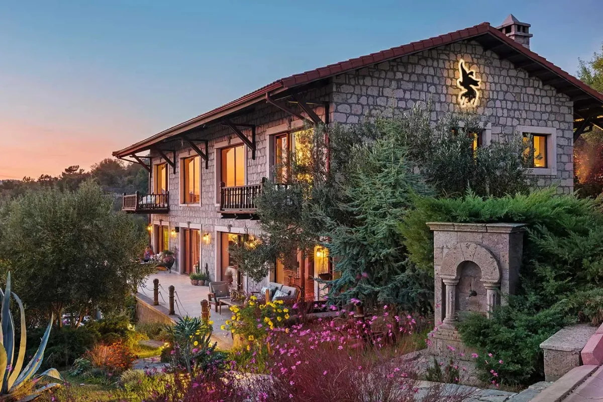 Doğa içinde konumlanan taş mimarili Simurg Inn butik otel, gün batımında aydınlatılmış bahçe ve teras alanı.