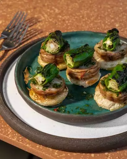 Bodrum'un gastronomik deneyimlerini çağrıştıran, rustik bir seramik tabakta servis edilen, altında çıtır ekmek, üzerinde ince dilimlenmiş et veya mantar katmanları ve tepesinde ızgara yeşil biber ile zengin ot sosu bulunan beş adet zarif atıştırmalık.