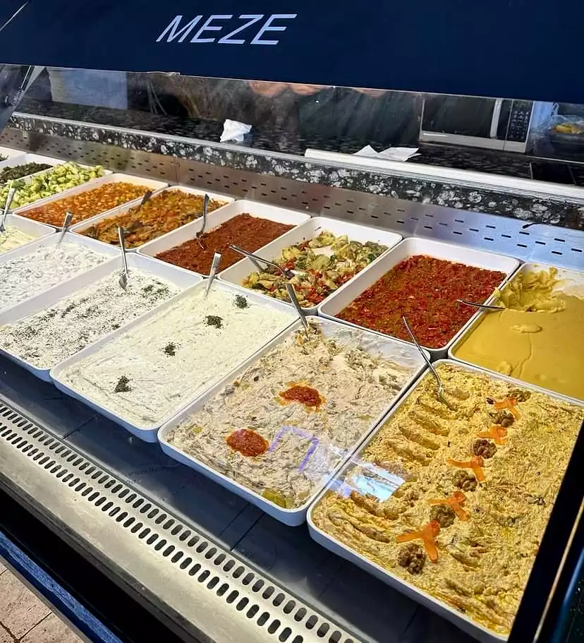 Bodrum'un en iyi restoranlarında bulunabilecek, yoğurtlu soslar, domates ve biber ezmeleri, cevizli havuçlu salata gibi Ege'nin zenginliğini yansıtan birçok lezzetli mezenin sergilendiği bir buzdolabı vitrini.