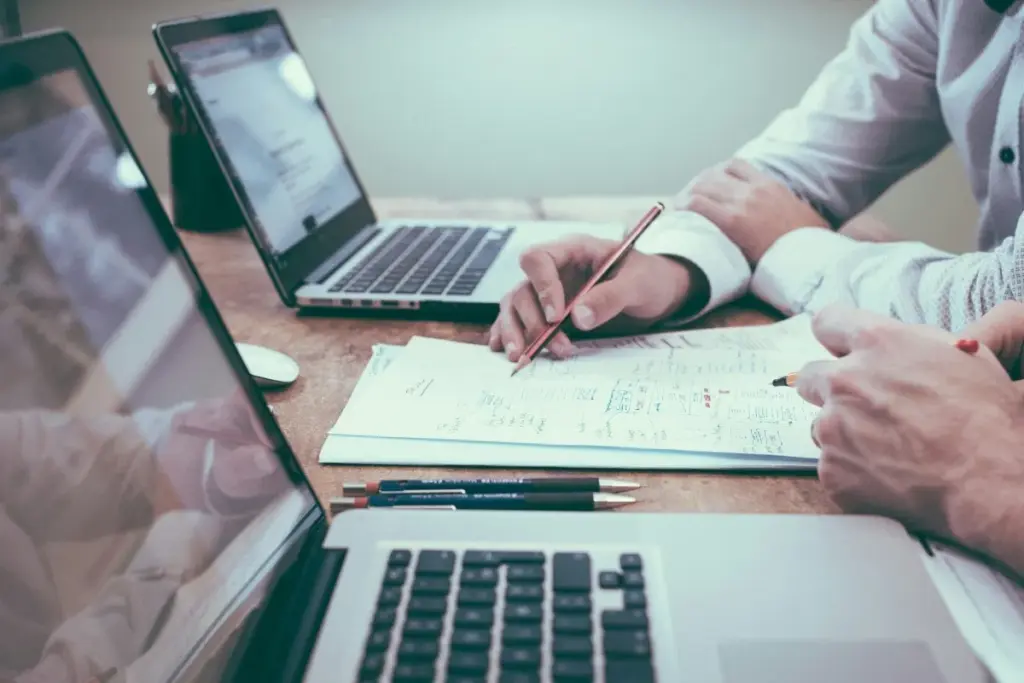 İki kişi masada laptop ve belgeler üzerinden finansal strateji toplantısı yapıyor.