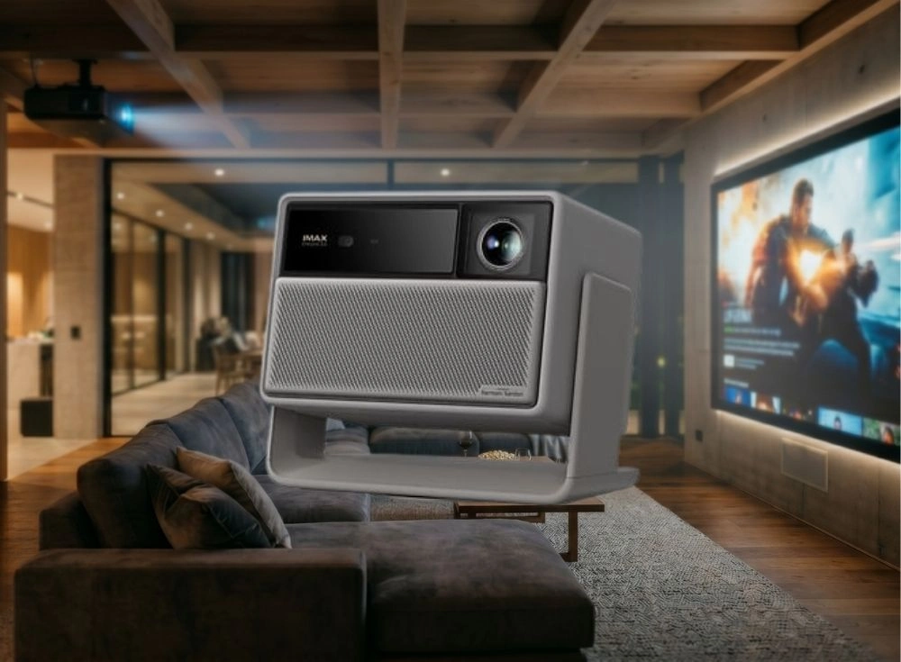 Gri renkli, Harman Kardon hoparlör ızgarasına ve üst kısmında IMAX Enhanced logosu ile bir lense sahip modern XGIMI Horizon 20 ev sineması ve oyuncu projeksiyonu, koyu renkli bir kanepenin önünde durarak arkadaki geniş ekrana canlı bir aksiyon filmi yansıtıyor.