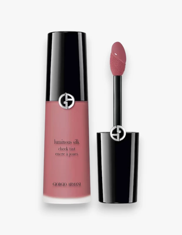 Sonbaharda trend olan allık tonları arasında yer alan Dusty Rose görünümünü yansıtan, beyaz arka plan üzerinde konumlanmış Giorgio Armani Luminous Silk Cheek Tint 62 Delicate Mauve tonundaki yanak renklendiricisi; şeffaf şişesi, siyah kapağı üzerindeki gümüş renkli Giorgio Armani logosu ve ürüne batırılmış kadifemsi sünger uçlu aplikatörüyle sergileniyor.