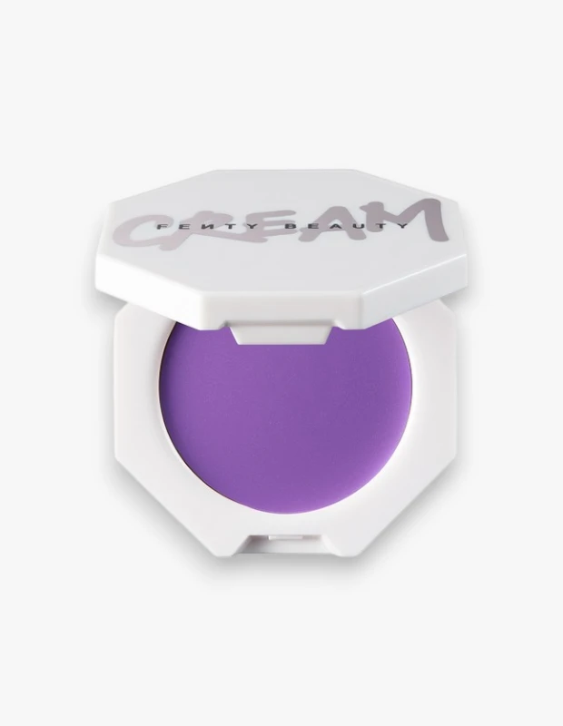 Fenty Beauty Cheeks Out Freestyle Krem Allık Drama Class rengi, hafifçe aralık duran sekizgen beyaz bir ambalaj içinde canlı mor tonuyla dudak ve yanaklara uygulanmaya hazır şekilde sunularak ürünün işlevselliğini vurguluyor.