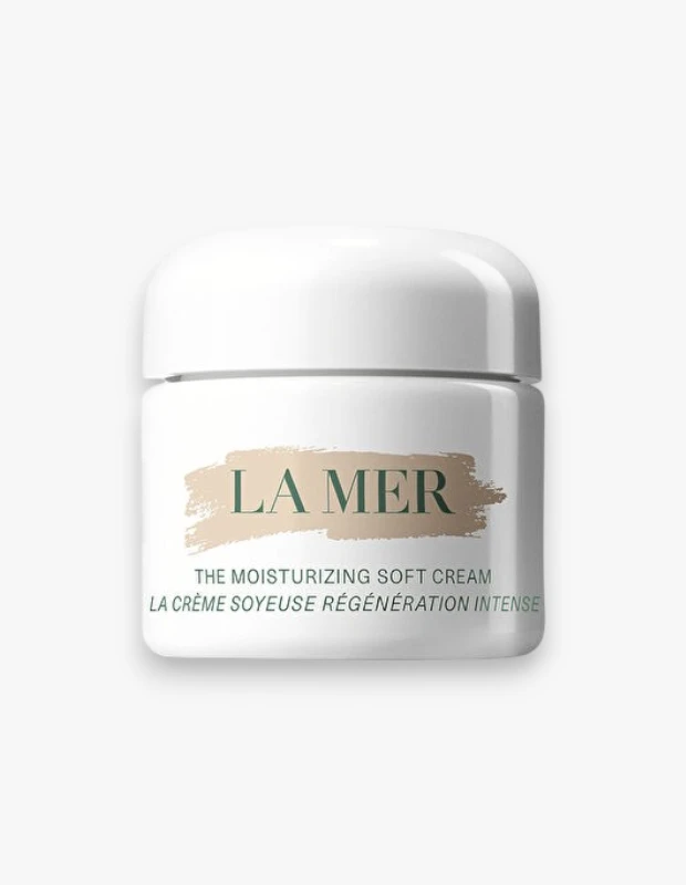 Beyaz bir zeminde duran, üzerinde açık bej rengi bir fırça darbesi deseniyle La Mer yazısı ve altında The Moisturizing Soft Cream ibaresi bulunan, yuvarlak hatlı, parlak beyaz renkli La Mer nemlendirici krem kavanozu.