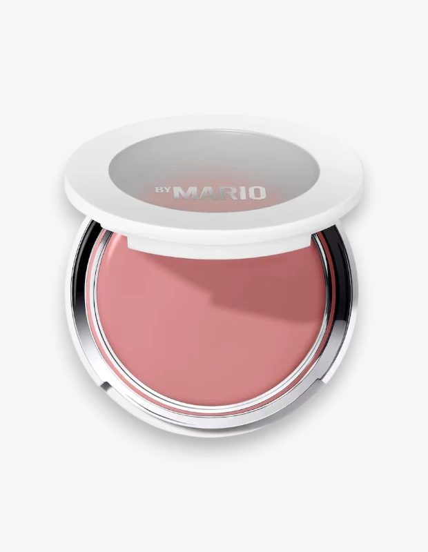 Sonbaharda trend olan allık tonları arasında öne çıkan doğal pembe görünümü yansıtan Makeup By Mario Soft Pop Plumping Blush Veil, açık beyaz bir zeminde hafifçe aralık duran yuvarlak beyaz kompaktı, gümüş renkli detayları ve kremsi dokusuyla sergileniyor.