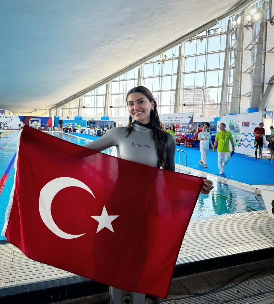 Türk serbest dalış sporcusu Yağmur Ergün, uluslararası yüzme havuzunda Türk bayrağıyla poz veriyor.