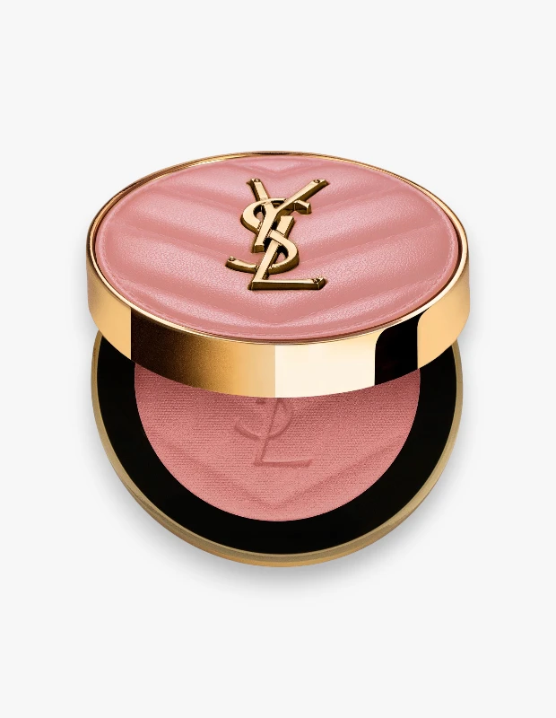 Altın renkli kenarları ve kapağında kapitone desenli pudra pembe deri üzerine altın YSL logosu bulunan, hafifçe aralık duran yuvarlak bir YSL allık kutusu görülüyor; içinde gül kurusu tonlarında ve üzerinde belirgin YSL logosu olan, cilde pürüzsüzleştirici etki sağlayan bir allık bulunuyor.
