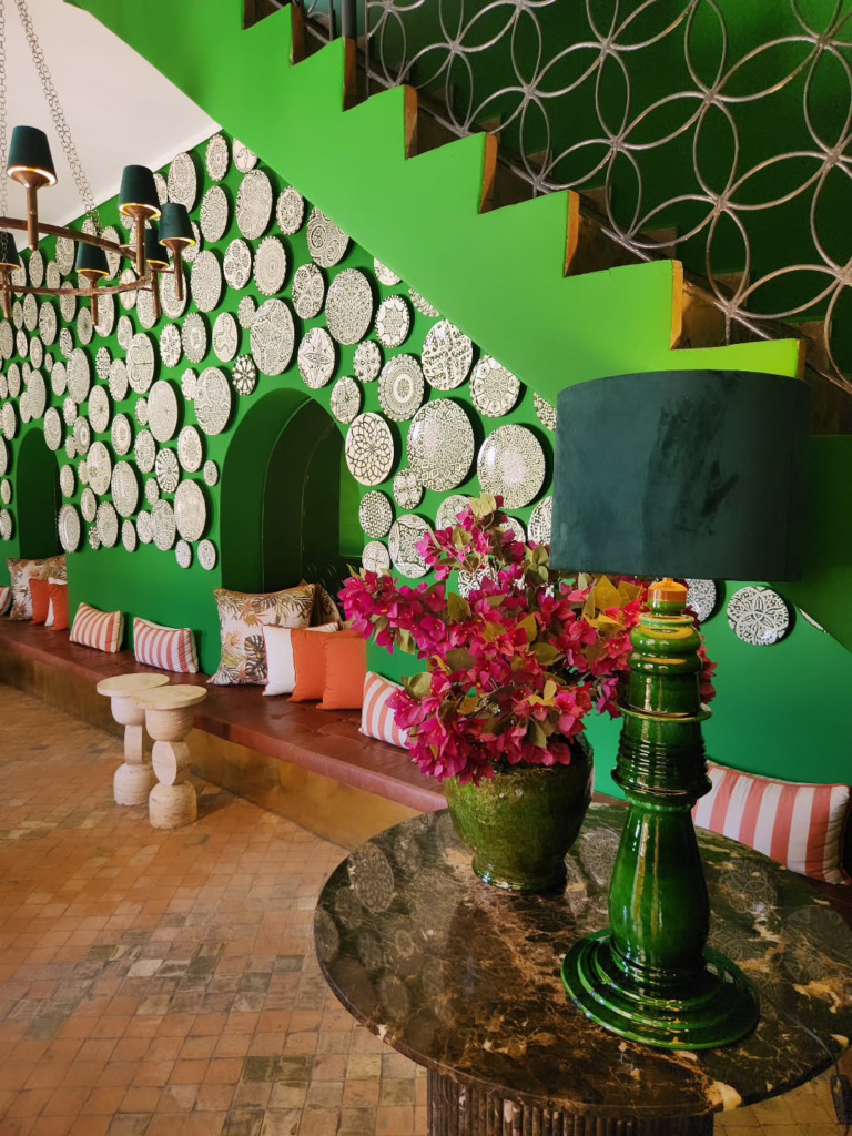 Marakeş’in kalbindeki Café Arabe restoranının, yeşil duvarlar üzerindeki desenli tabaklarla süslü canlı iç mekânı, turuncu ve çizgili yastıklarla donatılmış uzun oturma alanı, fıstık yeşili seramik lambası ve fuşya çiçekleriyle enerjik ve davetkar bir atmosfer sunuyor.