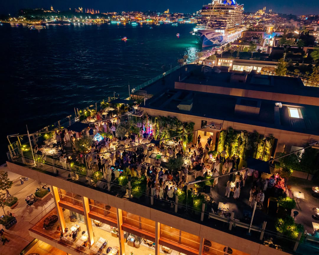 Galataport'ta yer alan Frankie İstanbul'un Boğaz ve Tarihi Yarımada manzaralı terasında, akşam saatlerinde canlı müzik ve DJ performanslarıyla eğlenen çok sayıda insanın görüldüğü, ışıl ışıl ve hareketli bir manzara.