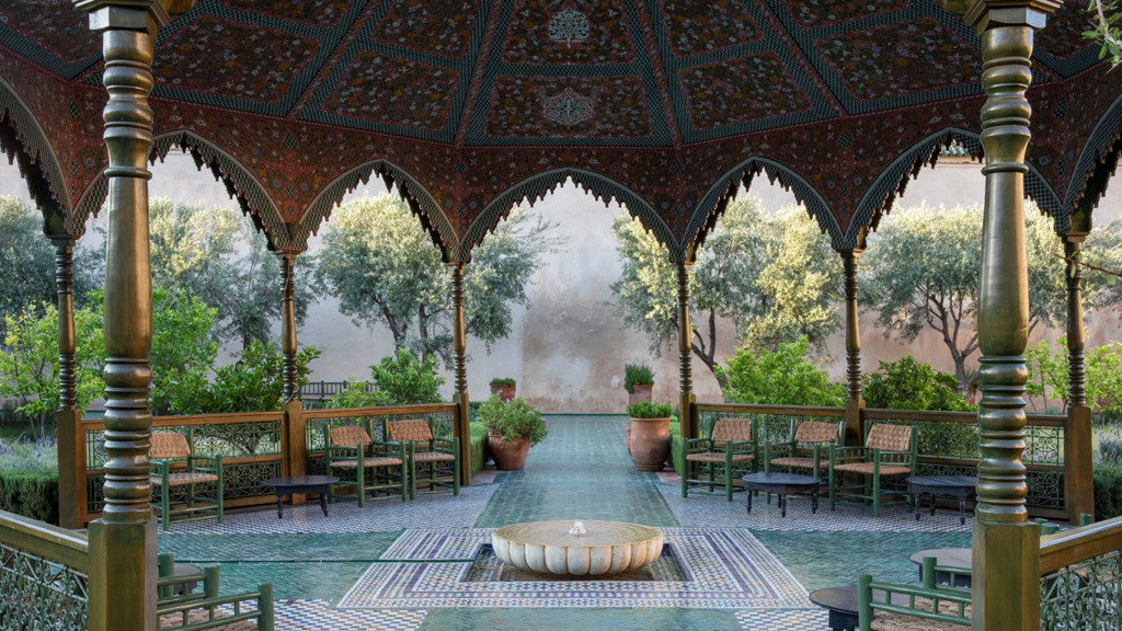 Marakeş Seyahat Rehberi'mizde bahsettiğimiz Le Jardin Secret'in zarif pavilyonunda, Fas mimarisinin renklerle bezenmiş karmaşık ahşap işçiliği, yeşil tonlardaki mozaik zemin ve ortadaki fıskiye, ziyaretçilere adeta bir rüya gibi huzurlu bir vaha sunuyor.