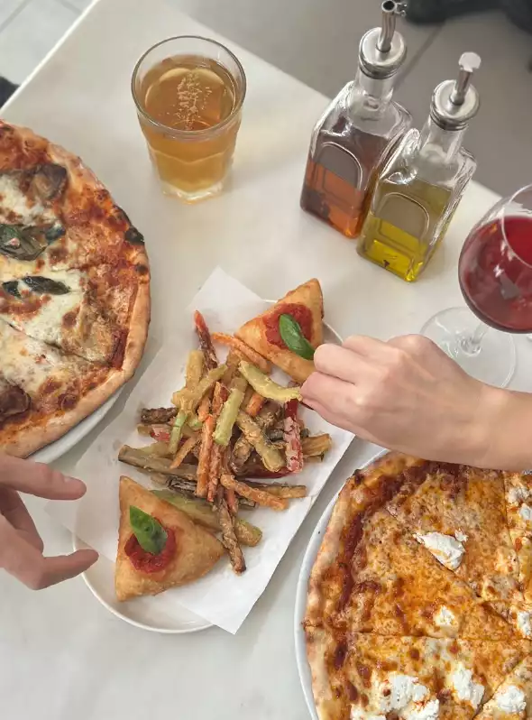 Pizzeria Il Pellicano’da pizza ve başlangıç tabağı servisi.