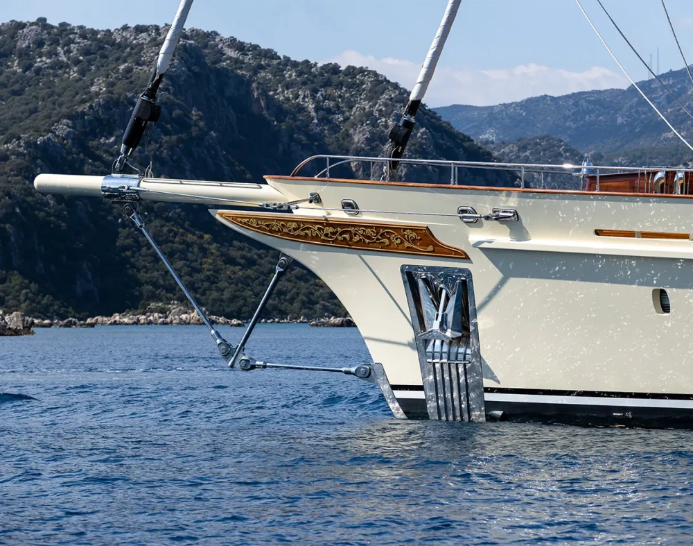 Masmavi denizde ilerleyen, parlak beyaz gövdesi ve modern tasarımıyla dikkat çeken, Türk üretimi Ares Yachts Simena yelkenli süper yatının baş iskele tarafından çekilmiş görkemli bir fotoğrafı, gökyüzünün altında.