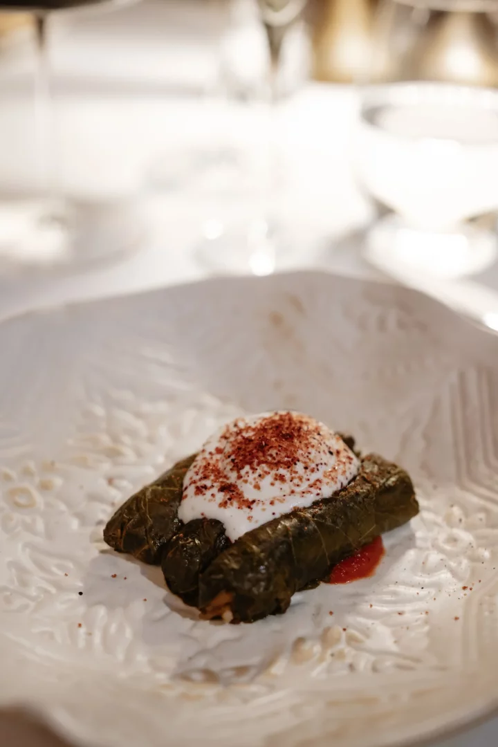 Museum Hotel bünyesindeki Lila Restaurant'ta sunulan, üzeri krem beyaz yoğurt ve kırmızı baharatlarla zenginleştirilmiş, özenle hazırlanmış üç adet yaprak sarma, zarif işlemeli beyaz bir tabakta iştah açıcı bir şekilde sunuluyor.