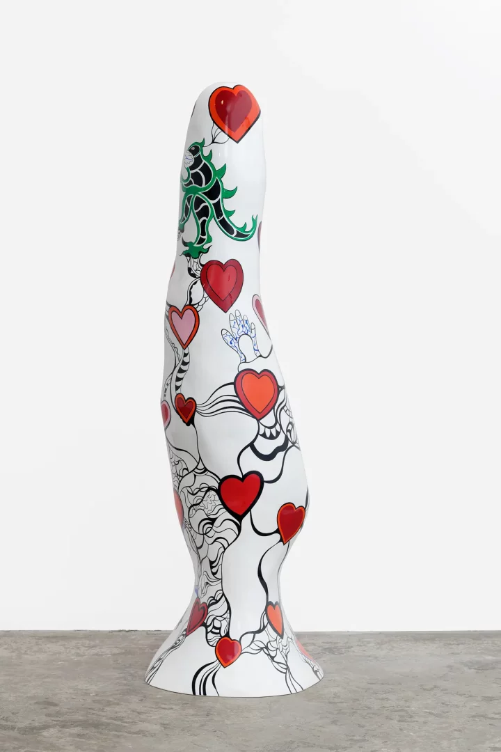 Niki de Saint Phalle'ın sanatsal estetiğini yansıtan, obelisk formunda, beyaz yüzeyine kırmızı ve pembe kalpler, kıvrımlı siyah çizgiler ve yeşil-siyah figürler işlenmiş, organik hatlara sahip uzun ve renkli bir heykel.