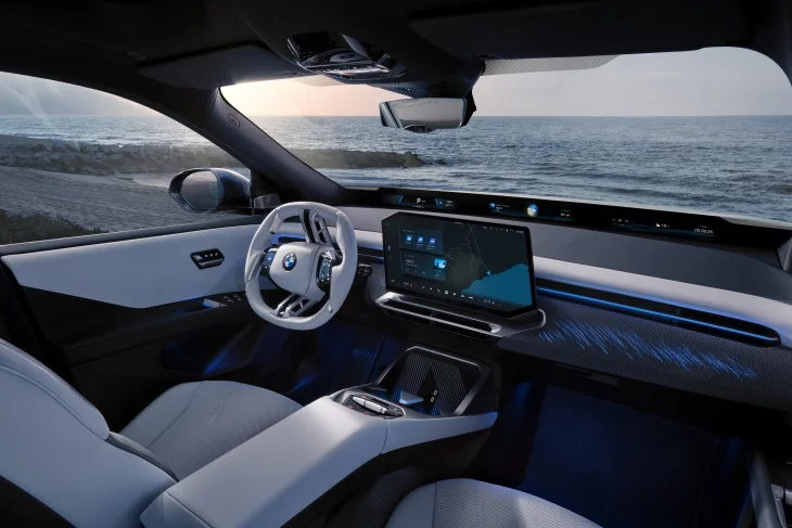 Dalgalı deniz manzarası eşliğindeki yeni BMW iX3'ün iç mekanı, minimalist beyaz direksiyonu, büyük merkezi bilgi ekranı, ön cam boyunca uzanan BMW Panoramic Vision ve ışıklandırılmış desenli ön paneliyle Neue Klasse tasarımının dijital kokpit odaklı elektrikli gelecek vizyonunu modern bir şekilde yansıtıyor.