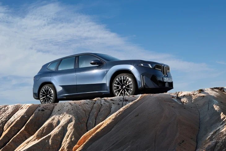 Yeni BMW iX3, kayalık zemin üzerinde yan profil görünümüyle.