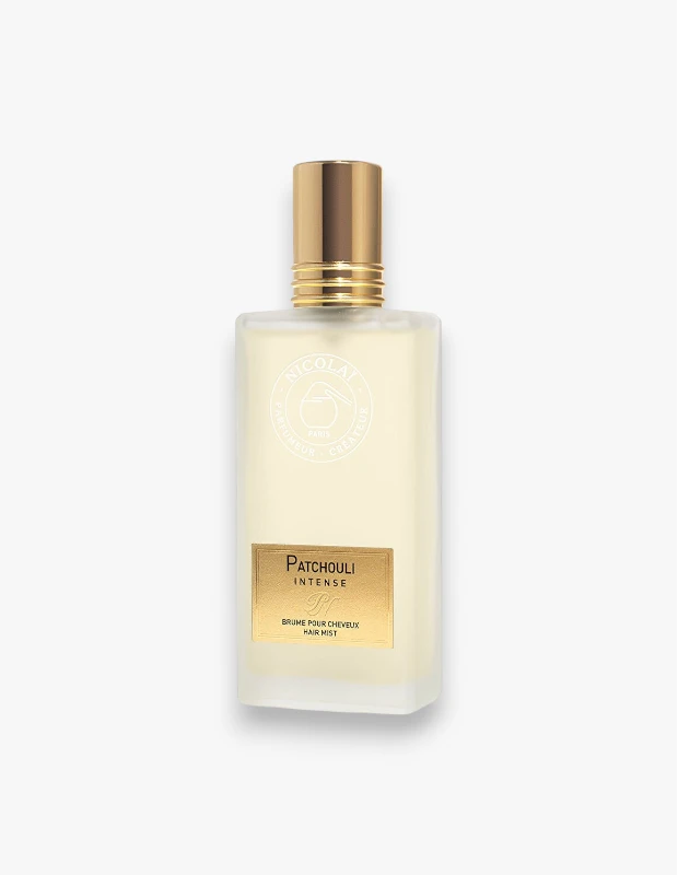 Altın rengi kapaklı, buzlu dikdörtgen cam şişe içinde soluk sarı renkli Nicolai Patchouli Intense saç misti, üzerinde altın etiketle ürün adı ve HAIR MIST yazısı ile beyaz bir arka plan üzerinde belirgin bir şekilde duruyor.