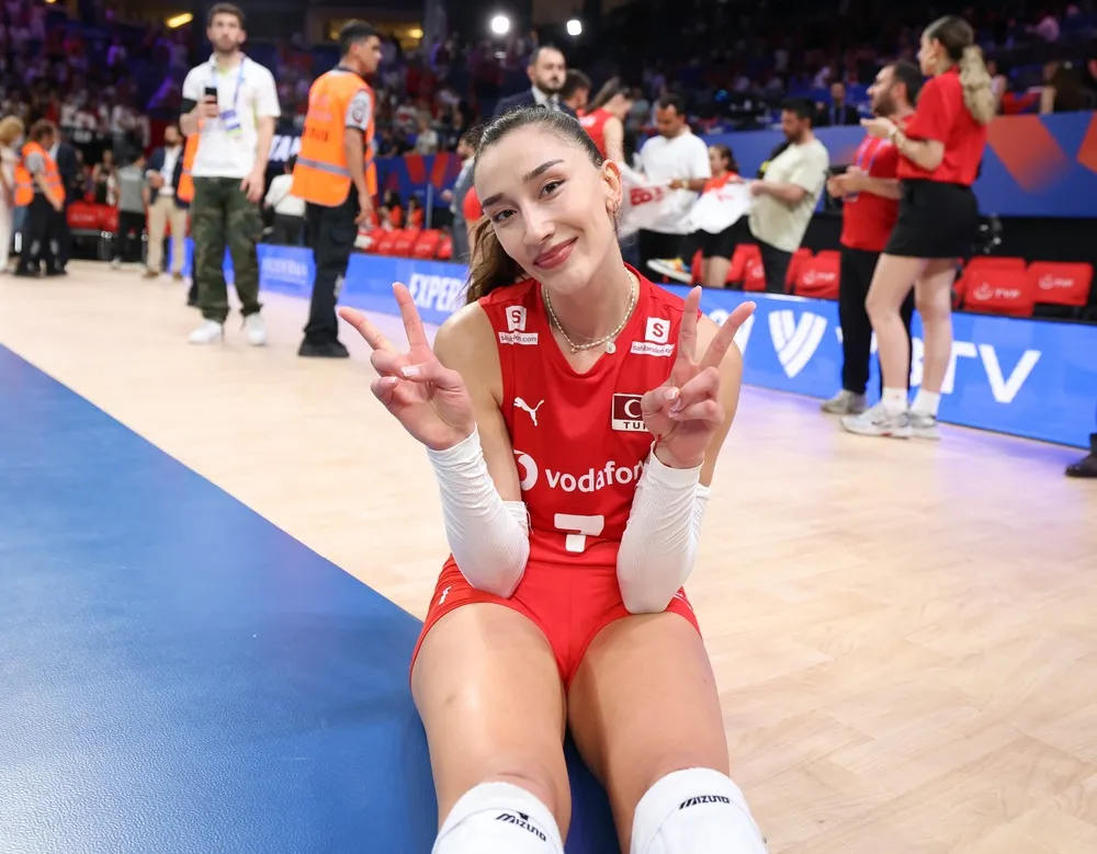 Kırmızı voleybol forması ve beyaz kolluklarıyla saha zemininde otururken her iki eliyle zafer işareti yapan ve gülümseyen Hande Baladın, ödüllerini takiben duyduğu memnuniyeti yansıtıyor.