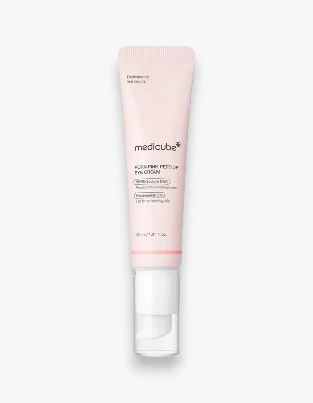 Bir beyaz arka plan üzerinde dikey duran, üzerinde Medicube PDRN Pink Peptide Eye Cream yazan, pembe renkli ve şeffaf kapaklı beyaz pompalı bir göz kremi tüpü, yorgun göz çevresini canlandırmaya yardımcı olan PDRN (Sodyum DNA) ve daha sıkı bir görünüm sağlayan Niasinamid %5 gibi etkili içeriklerini vurguluyor.