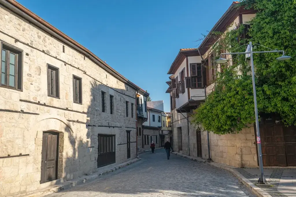 Arnavut kaldırımlı dar bir sokakta, yeşilliklerle çevrili geleneksel taş ve ahşap yapılarıyla Tarsus'un kadim ruhunu ve kültürel zenginliğini yansıtan bu otantik tarihi evler, Mersin'de gezilecek yerler listenizin önemli duraklarından biridir.