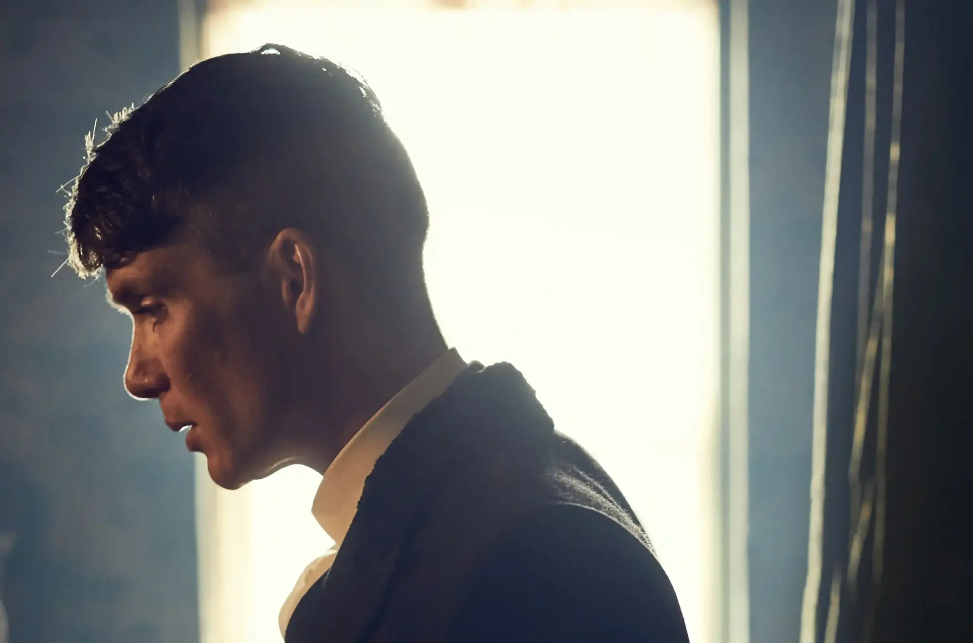 Peaky Blinders'ın karizmatik karakteri Thomas Shelby'yi canlandıran Cillian Murphy, ikonik undercut saç tıraşı ve koyu takım elbisesiyle yandan çekilmiş bu profil fotoğrafında, modern erkek modasında yarattığı zamansız gentleman estetiğini ve güçlü duruşunu sergiliyor.