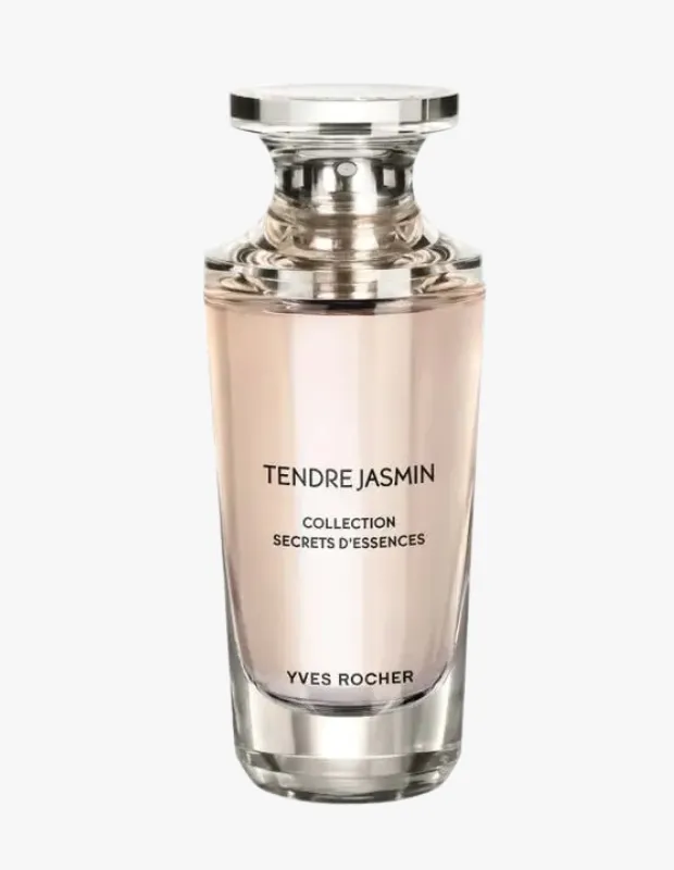 Beyaz bir arka plan üzerinde zarifçe duran, pembe bej renkli şeffaf cam şişesinde TENDRE JASMIN yazılı, COLLECTION SECRETS D'ESSENCES ve YVES ROCHER markası belirgin şekilde görünen, gümüş renkli metal kapaklı bu gelin parfümleri narin ve çekici bir kokuyu temsil ediyor.