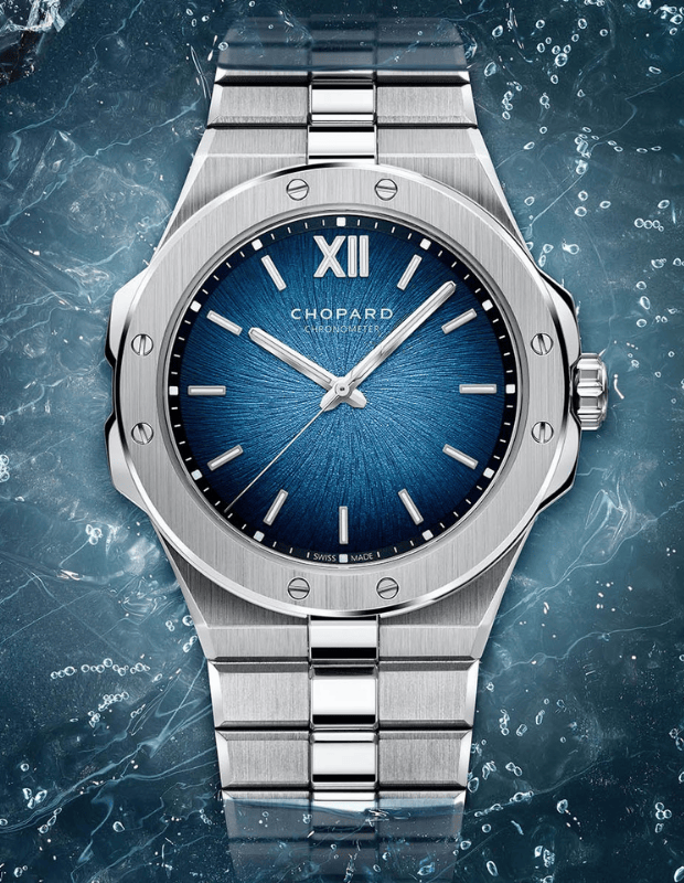 Buz dokulu arka plan üzerinde sergilenen, mavi güneş ışını desenli kadranlı ve paslanmaz çelik bilezikli Chopard spor-lüks saat.
