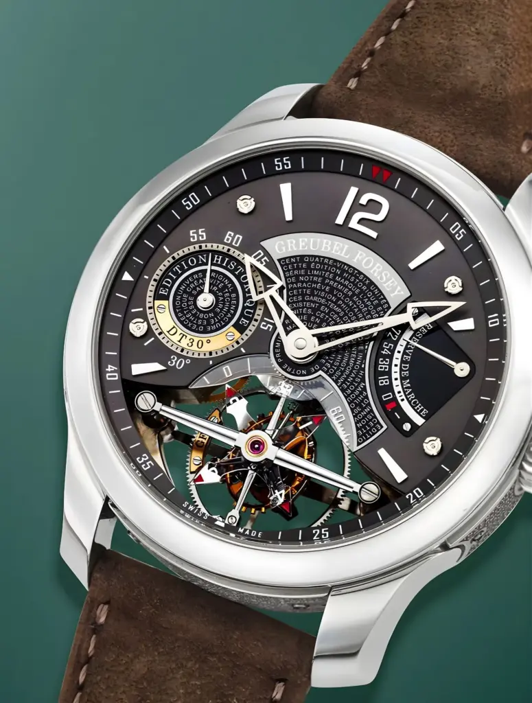 Yeşil arka plan önünde sergilenen, açık kahverengi deri kayışlı Greubel Forsey komplikasyon saati; açık kalibre yapısı, döner tourbillon mekanizması ve çok katmanlı göstergeleriyle detaylı kadran tasarımı.