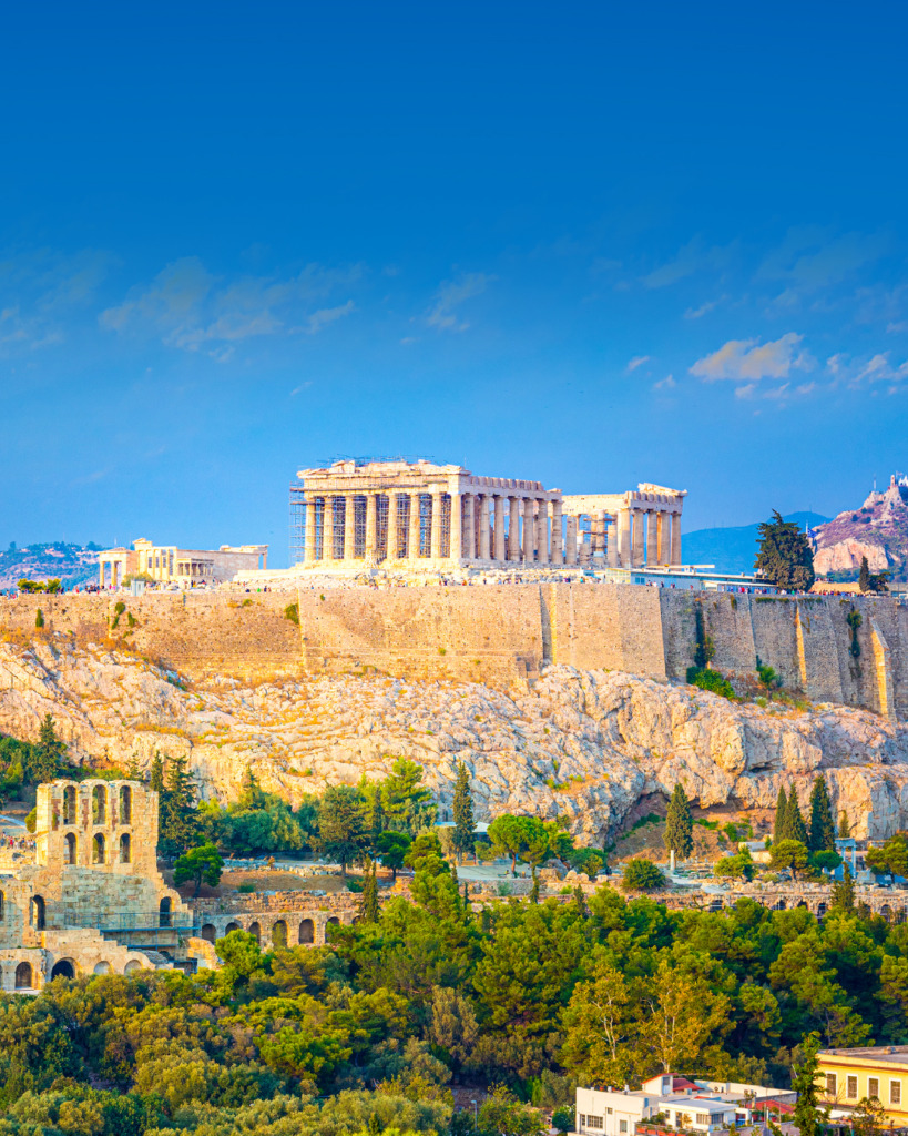 Atina şehrinin Akropolis başta olmak üzere antik yapılarının göz alıcı mimarisini ve binlerce yıllık tarihini gözler önüne seren bir seyahat destinasyonunu temsil eder. Altın tonlardaki ışıkla aydınlanan mermer yüzeyler ve berrak gökyüzü altında uzanan yemyeşil tepeler, şehrin hem mitolojik hem de dingin atmosferini yansıtır. Antik kalıntıların modern Akdeniz enerjisiyle iç içe geçtiği, geçmişle bugünün eşsiz bir armoni içinde yaşandığı bir deneyim sunar.
Öne Çıkan Detaylar:
- Atina Akropolisi ve antik çağın görkemli mimarisi
- Tarihi derinliği modern Akdeniz enerjisiyle harmanlayan atmosfer
- Kış ve ilkbahar aylarında şehrin mistik ve ışıl ışıl ambiyansı
Kimler Kullanıyor?: Geçmişin büyüleyici hikayelerine kulak vermek, antik dünyanın ihtişamını modern bir Akdeniz şehrinin canlılığıyla birleştiren bir deneyim yaşamak isteyenler için bu destinasyon idealdir. Tarihi ve kültürel keşiflerden hoşlanan, dingin bir kış ya da taze bir ilkbahar atmosferinde yeni yerler görmeyi arzulayan, ruhunu hem hüzünlü hem de romantik bir seyahatle beslemek isteyen herkes Atina'nın bu benzersiz çekiciliğini takdir edecektir.
