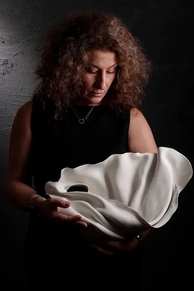 Tuba Önder Demircioğlu’nun “Karşılaşma” sergisi için hazırladığı porselen heykeli elinde tuttuğu portre, sanatçının üretim süreci ve serginin teması olan karşılaşma kavramını yansıtan kare.