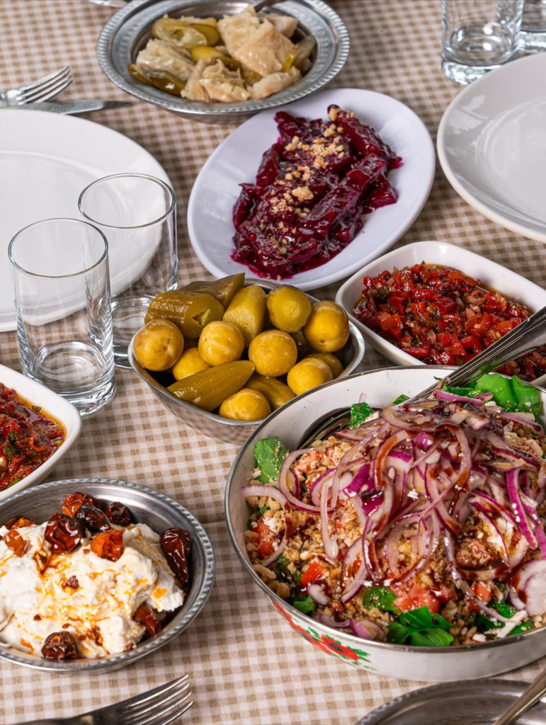 Ankara'nın en iyi meyhanelerinde dost sohbetlerine eşlik eden, üzerinde nar ekşili bol soğanlı salata, pancar ezmesi, turşular ve atom gibi geleneksel lezzetlerin modern sunumlarla buluştuğu zengin bir meze sofrası, kareli masa örtüsünde iştah açıcı görünüyor.
