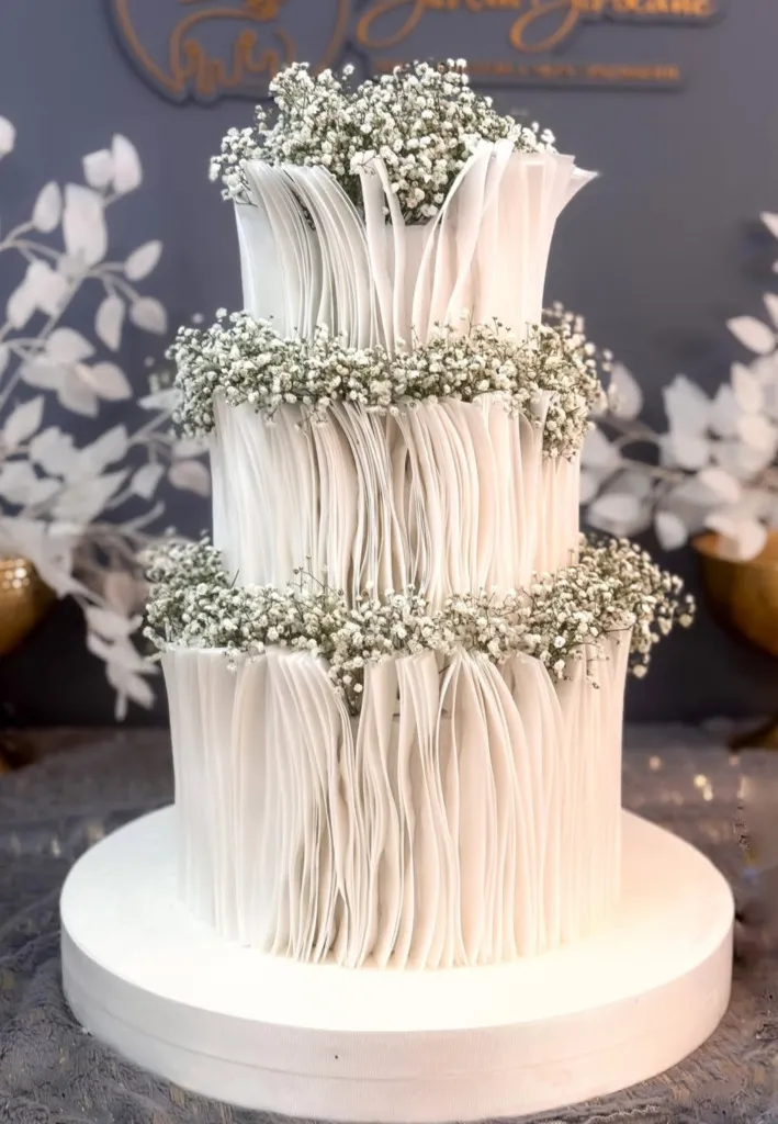 Bebek nefesi çiçekleriyle süslenmiş, katlı ruffled dokulu modern beyaz düğün pastası tasarımı