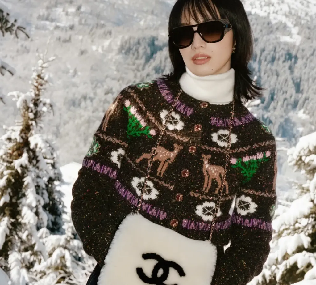Chanel kayak koleksiyonundan siyah üstüne renkli işlemeli bir mont giyen siyah güneş gözlüklü model