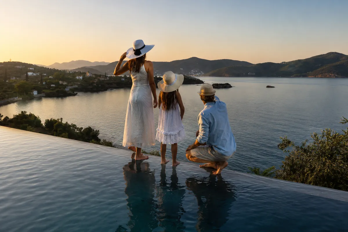 Gün batımında sonsuzluk havuzu kenarında deniz manzarasına bakan aile