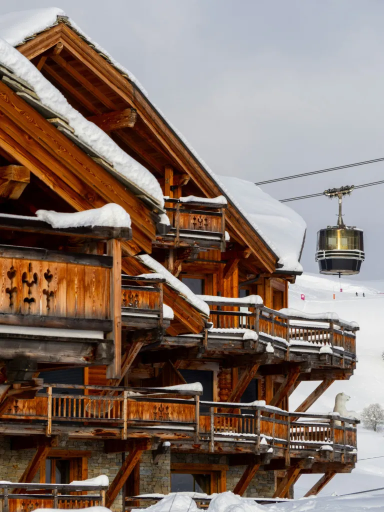 Alpler’de karla kaplı ahşap chalet ve teleferik manzarası