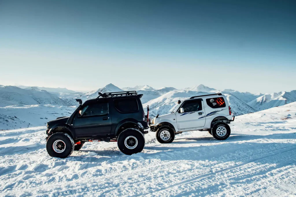 Karla kaplı dağlarda off-road araçlarının durduğu etkileyici kış manzarası.