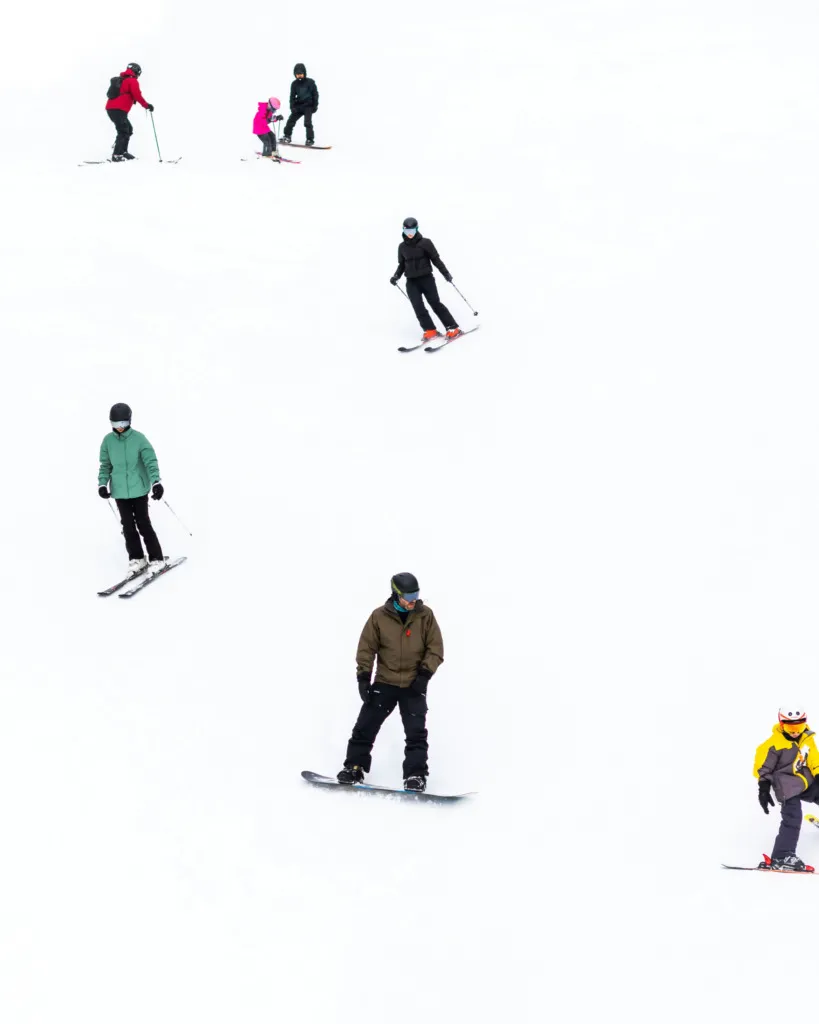 Kayak ve snowboard öğrenen yeni başlayanların grup dersi sırasında pistte ilerlemesi
