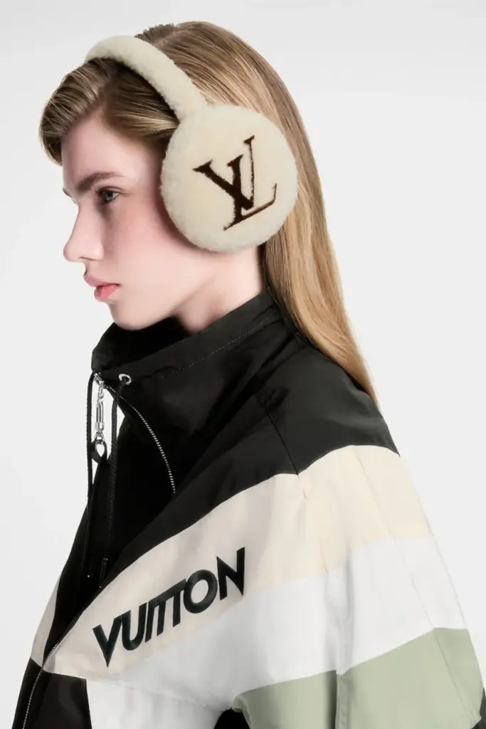 Louis Vuitton kayak koleksiyonundan LV logolu tüylü bir kulaklık takıp krem beyaz ve siyah renklerde kayak ceketi giyen bir model