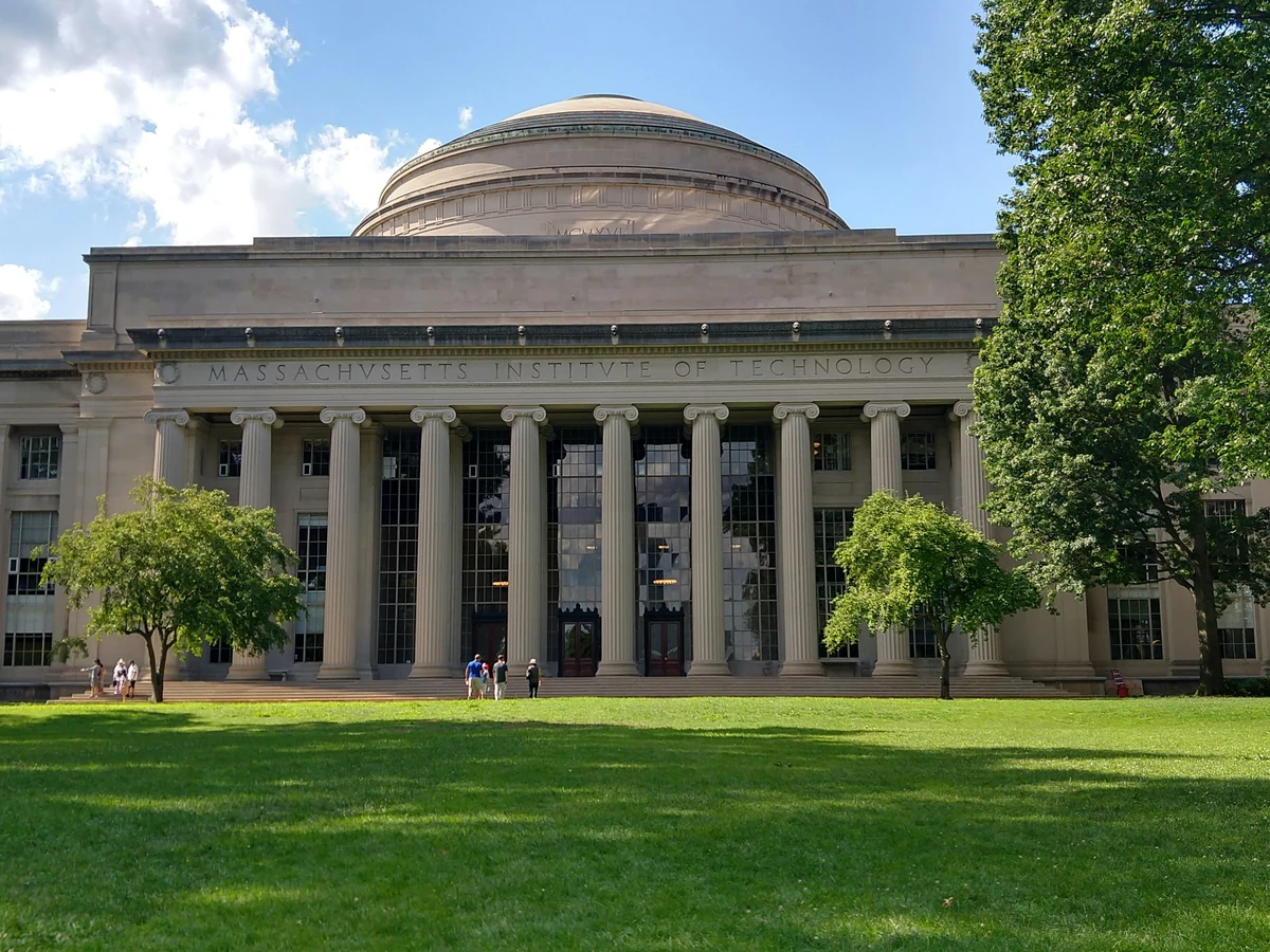 Massachusetts Teknoloji Enstitüsü'nün (MIT) ikonik kubbeli ana binası, parlak bir günde masmavi gökyüzü altında, kurumun dünyaca ünlü akademik ve bilimsel başarılarını temsil eden görkemli mimarisiyle kampüsün kalbinde yükseliyor.