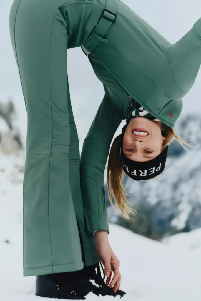 perfect moments markasının kayak koleksiyonundan yeşil kayak tulumu giyen ve siyah bere takan bir model