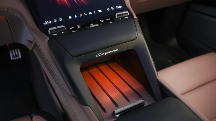 Porsche Cayenne Electric’in iç mekânında yer alan kablosuz şarj alanı ve ambiyans ışığıyla aydınlatılmış modern orta konsol detayları.