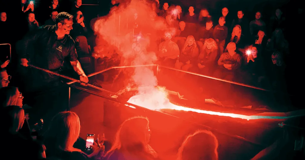 Reykjavik'te bilim ve sanatın birleştiği ilginç bir deneyim olan Lava Show'da, koruyucu gözlüklü bir gösterici 1100°C sıcaklığındaki erimiş lavı metal bir oluğa dökerken izleyiciler bu volkanik görsel şöleni cep telefonlarıyla kaydediyor ve parlayan kırmızı dumanın dramatik anlarına tanık oluyorlar.
