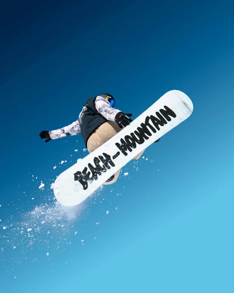 Snowboard sporcusunun havada yaptığı atlayış, mavi gökyüzünde kar sporu aksiyonu
