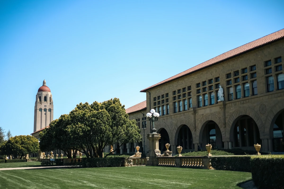 Güneşli bir California gününde, Stanford Üniversitesi kampüsünün ikonik kırmızı kiremit çatılı, kumtaşı rengi binaları, zarif kemerleri ve yemyeşil palmiye ağaçlarıyla çevrili ferah avlusu, üniversitenin görkemli atmosferini yansıtıyor.