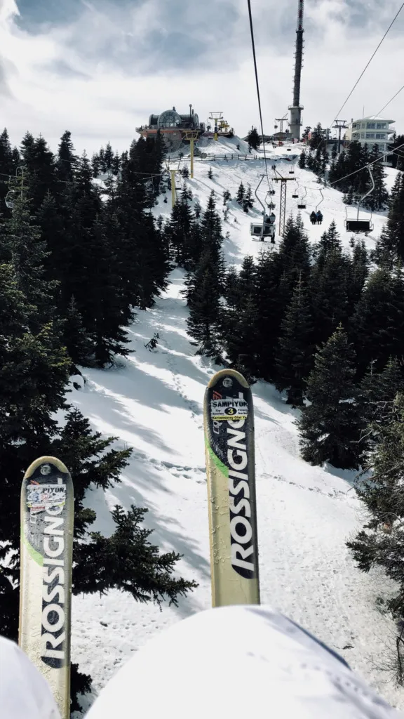 Türkiye’de bir kayak merkezinde chairlift üzerinde ilerleyen kayakçı ve karla kaplı pist manzarası