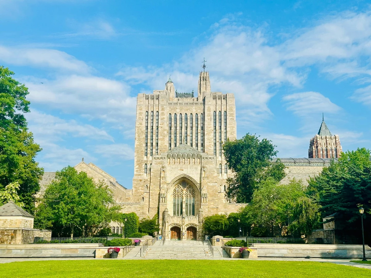 Yale Üniversitesi'nin yeşillikler içindeki tarihi kampüsünde, gotik mimarisiyle dikkat çeken, sivri kuleleri ve kemerli pencereleri olan gösterişli bir taş bina, derin akademik mirasını ve prestijli atmosferini yansıtıyor.