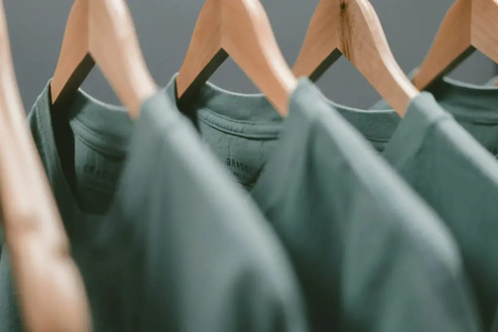 Aynı renkte düzenli şekilde askılara dizilmiş minimalist tişörtlerin yakın plan moda vitrini görüntüsü.